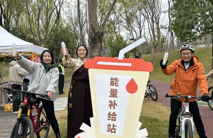 图为骑行者在能力补给站高兴举起理塘蜂蜜水.jpg